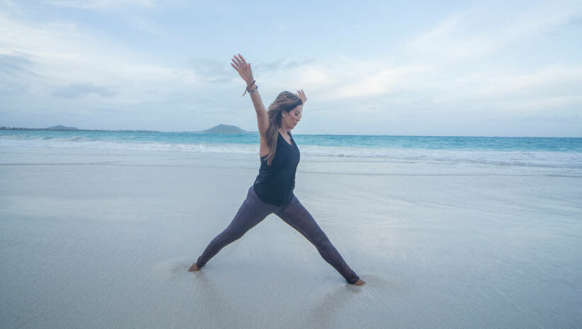 Desi Barlett in yoga pose on the beach demonstrating lessons of yoga