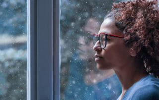 woman looking out window to reflect on prioritizing mental health